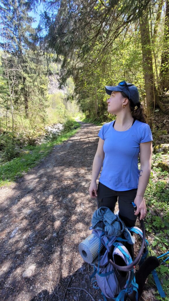 Femme en tenue de randonnée avec une casquette et un t-shirt bleu, dans la forêt.