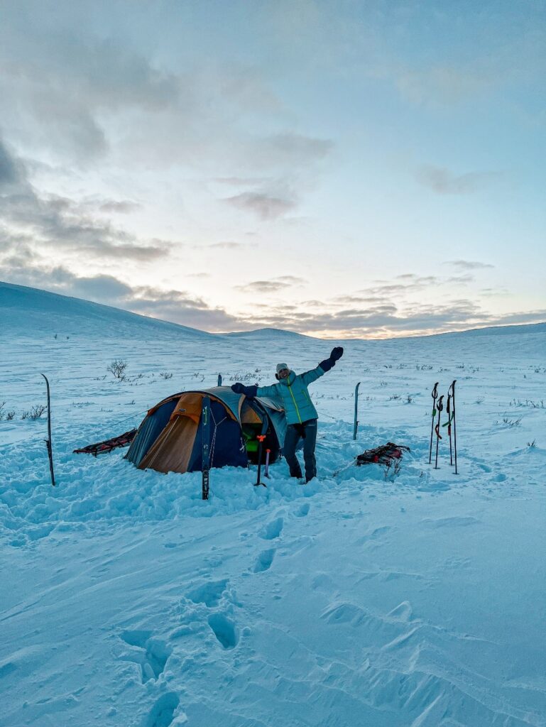 Une femme aventurière devant son campement dans un environnement polaire.