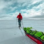 Un explorateur en expédition polaire qui traîne sa pulka dans la neige.