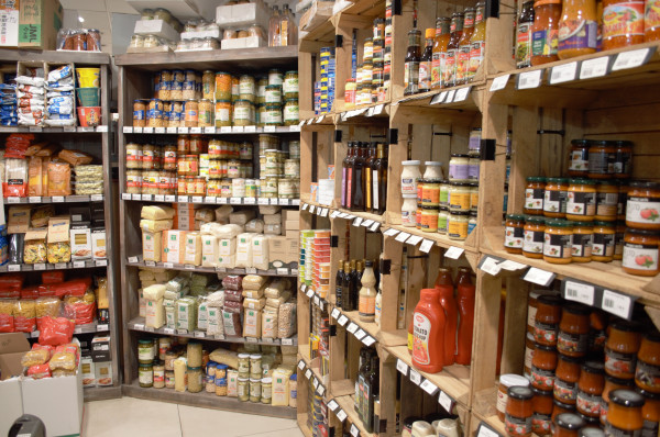 Etagères en bois remplies de produits dans une épicerie.