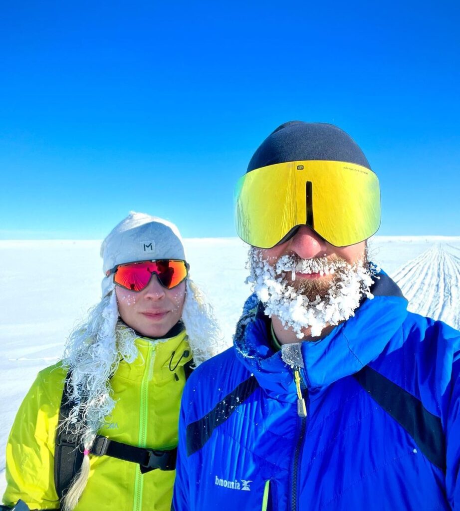 Un couple d'aventuriers en expédition polaire, le givre recouvrant leurs cheveux et la barbe.